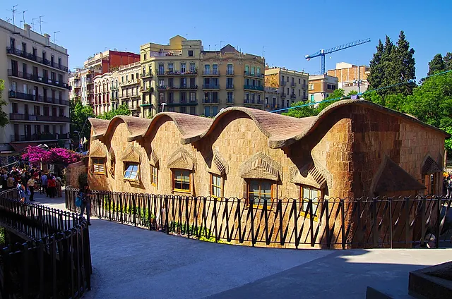 The Gaudí schools, a small low building with a wavy brick roof, in front of the apartment blocks of the Eixample